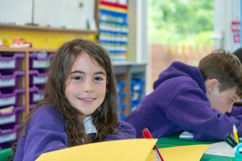 Pupils in a classroom setting, a girl smiles at the camera