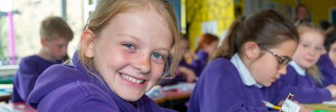 Pupils in a classroom setting, a girl smiles for the camera