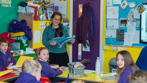 A teacher reads from a book to her class